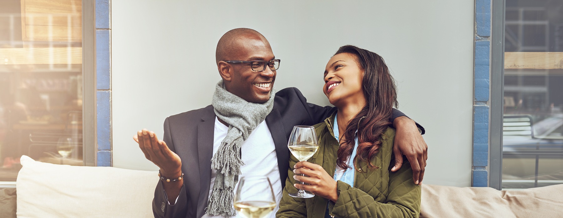 smiling couple drinking wine on an outdoor sofa
