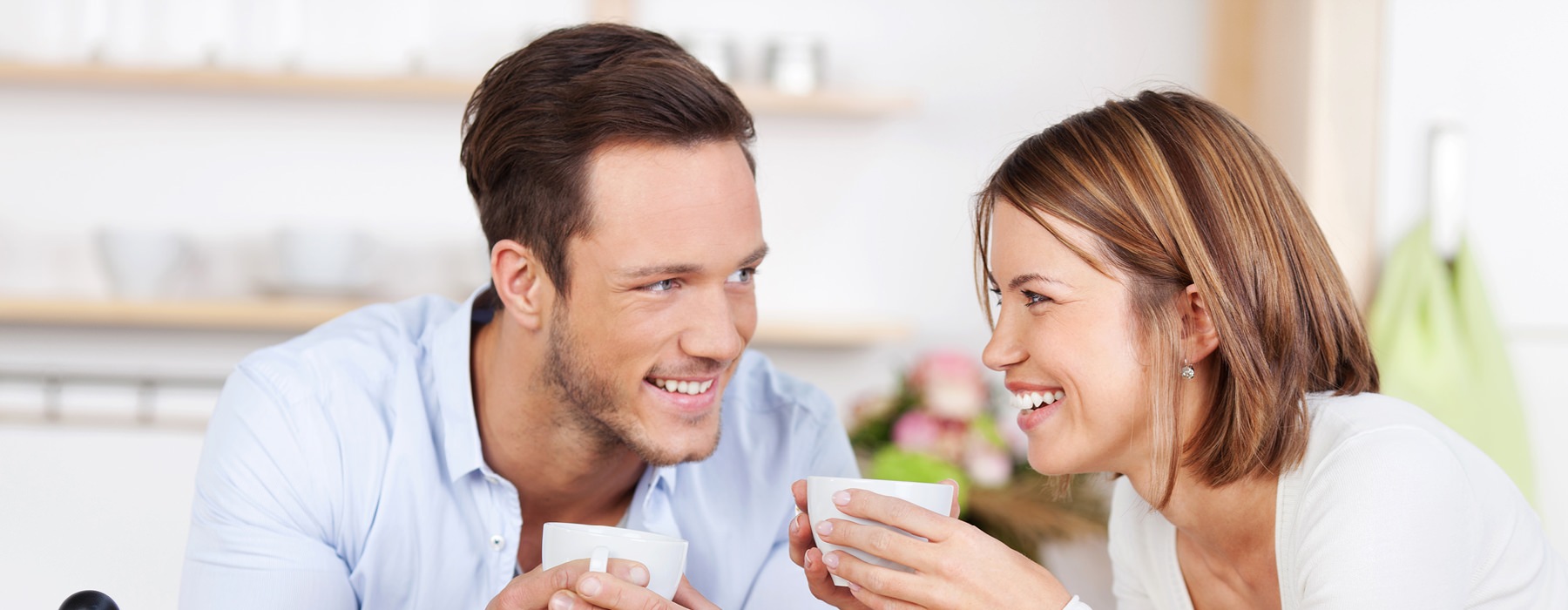 young couple smile at each other in the kitchen over breakfast